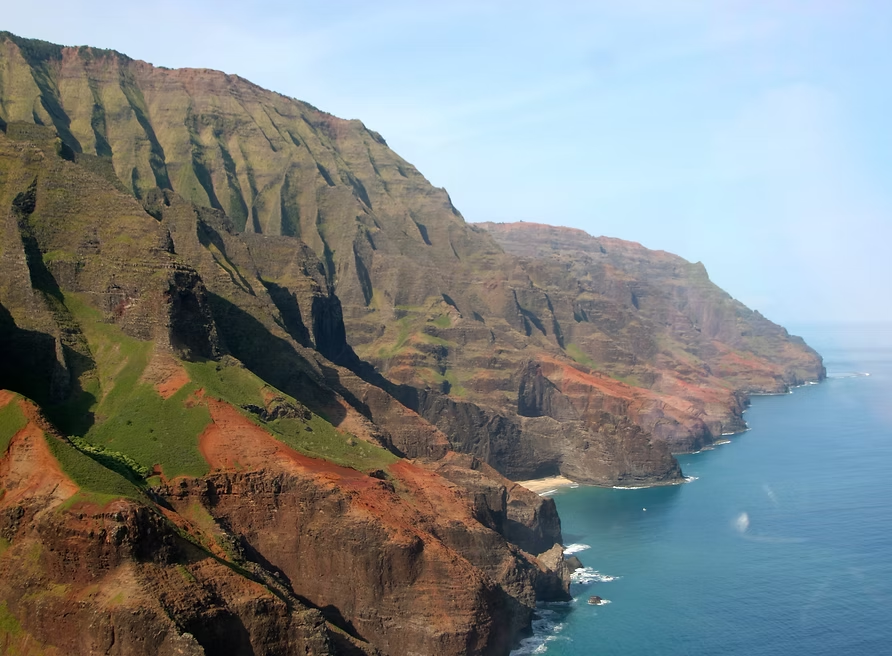 Côte escarpée et rocheuse avec des falaises vertes et brunes s'étendant dans l'océan Pacifique.