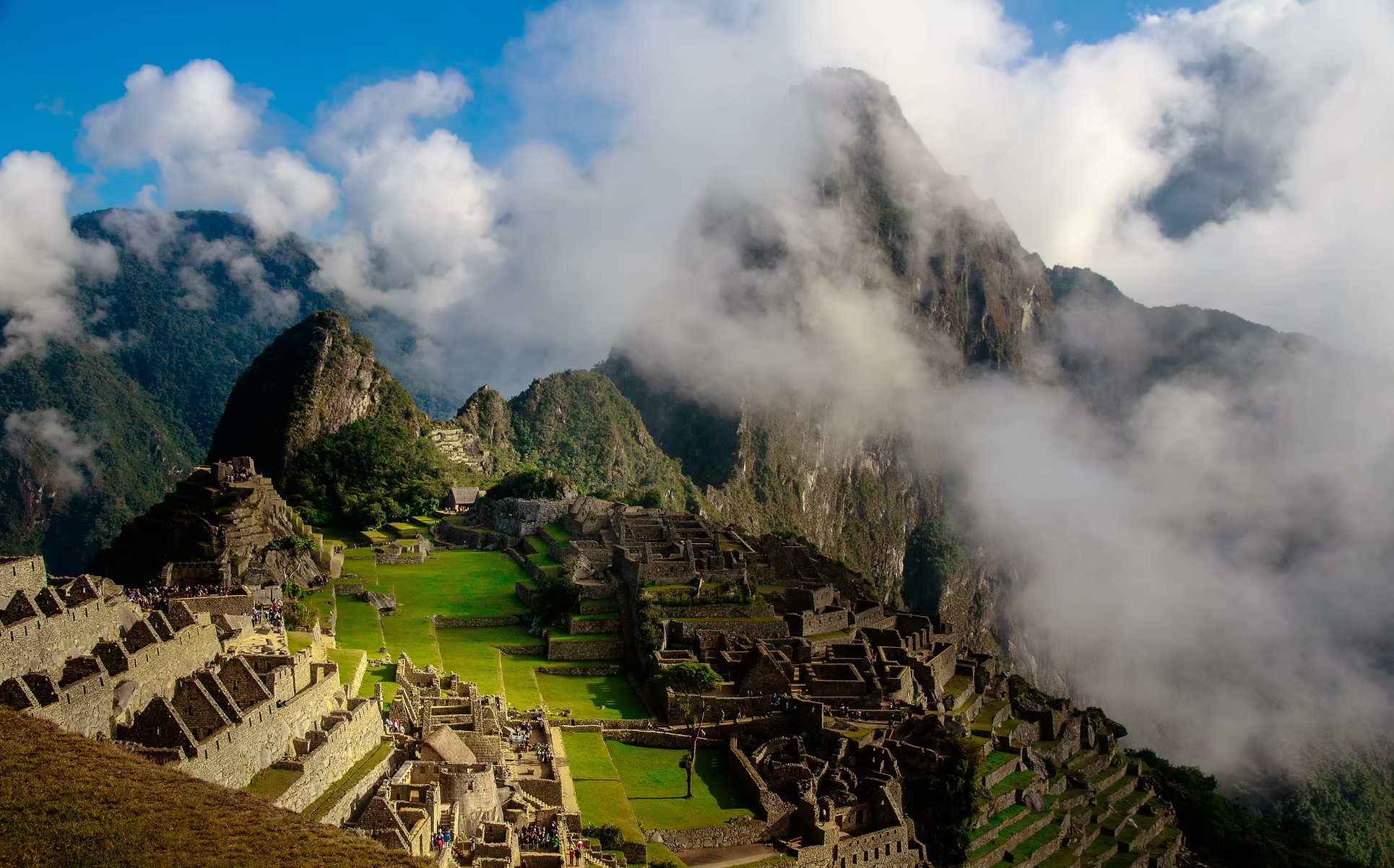 Ruines de Machu Picchu avec montagnes recouvertes de nuages en arrière-plan.