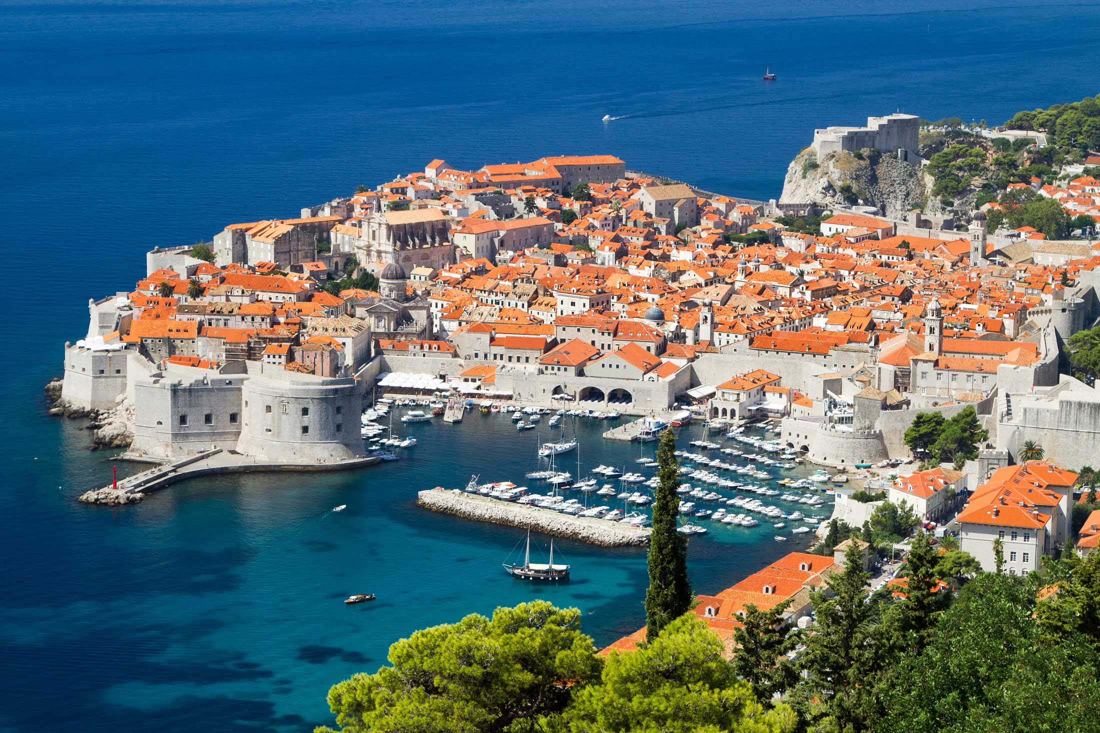 Vue aérienne de la vieille ville de Dubrovnik, Croatie, avec ses remparts, ses bâtiments en toits orange, et la mer bleue environnante.