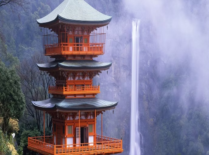 Pagode à trois étages en bois orange avec toit incurvé, située dans un paysage naturel avec cascade en arrière-plan.