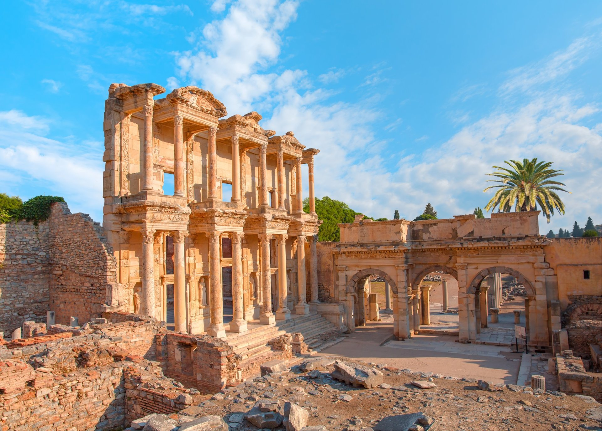 Ruines d'un ancien bâtiment romain avec des colonnes et des arches sous un ciel bleu avec quelques nuages.