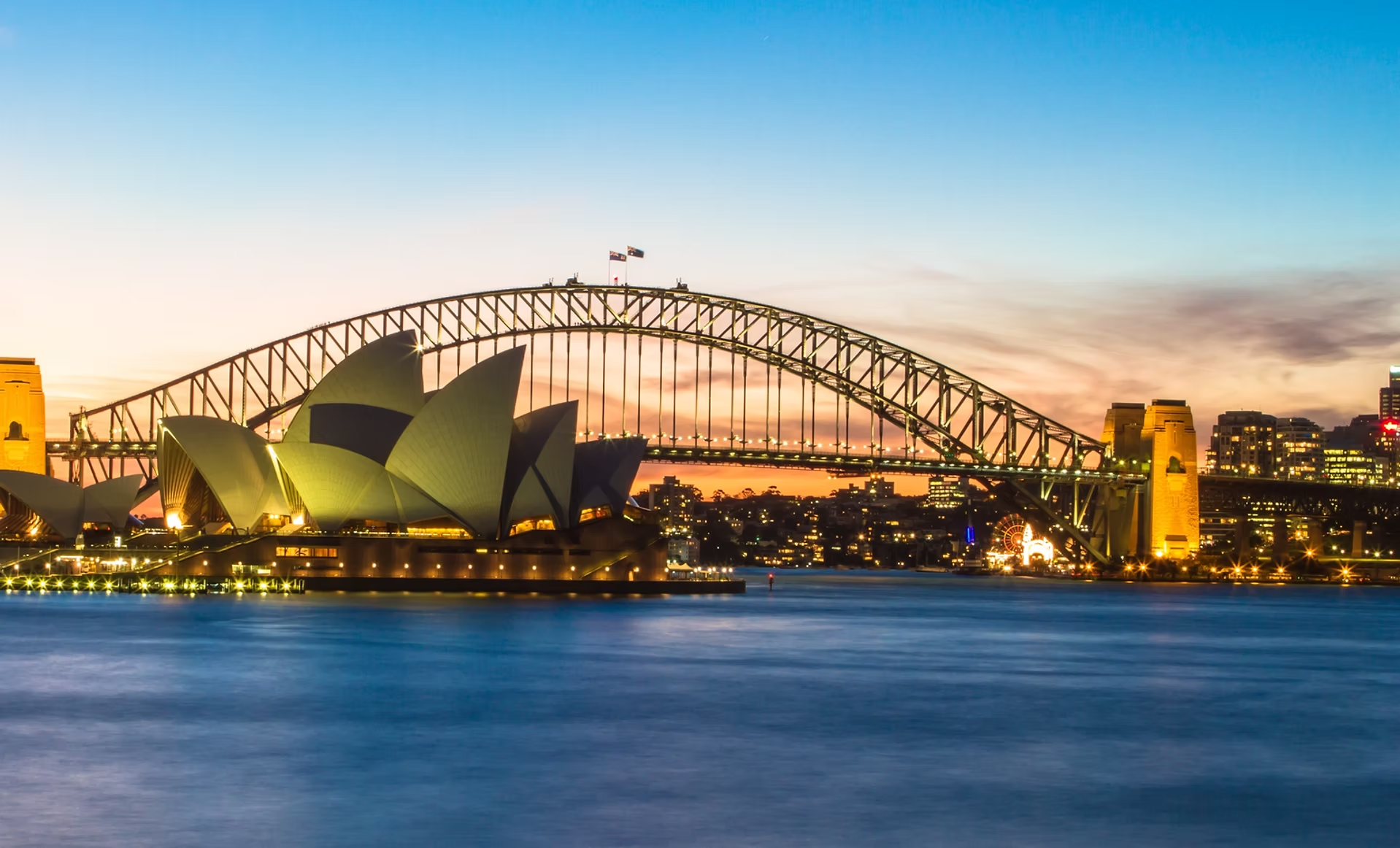 Vue de Sydney au crépuscule avec l'Opéra de Sydney et le Harbour Bridge éclairés.