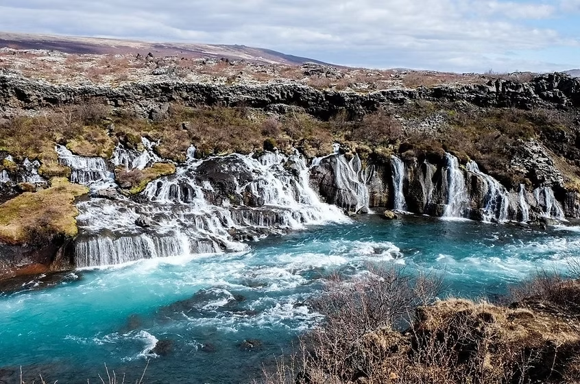 Cascade d'eau turquoise dans un paysage rocheux et aride en Islande.