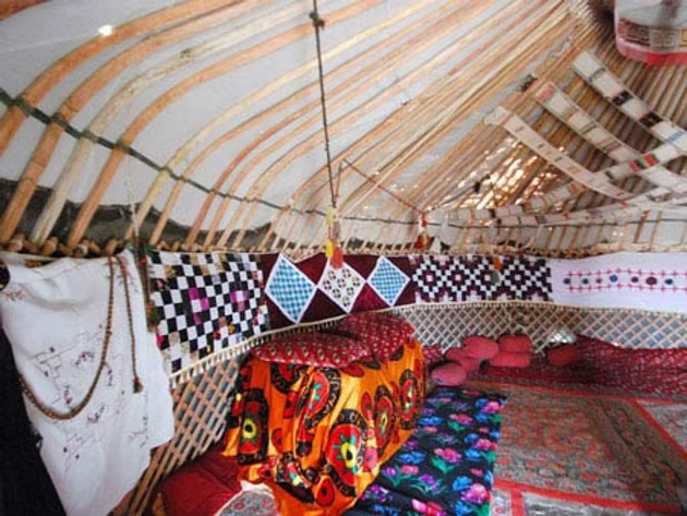 Intérieur d'une tente avec tapis colorés, coussins et décorations en tissu.
