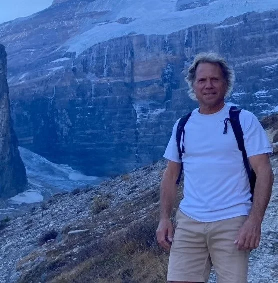 Homme en randonnée dans un paysage de montagnes et glaciers.