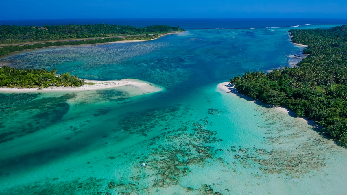 Vue aérienne d'une lagune turquoise entourée de plages de sable blanc et de forêts tropicales.