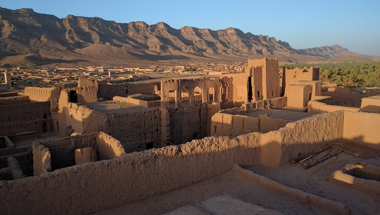 Ruines d'une ancienne ville en adobe avec montagnes en arrière-plan.