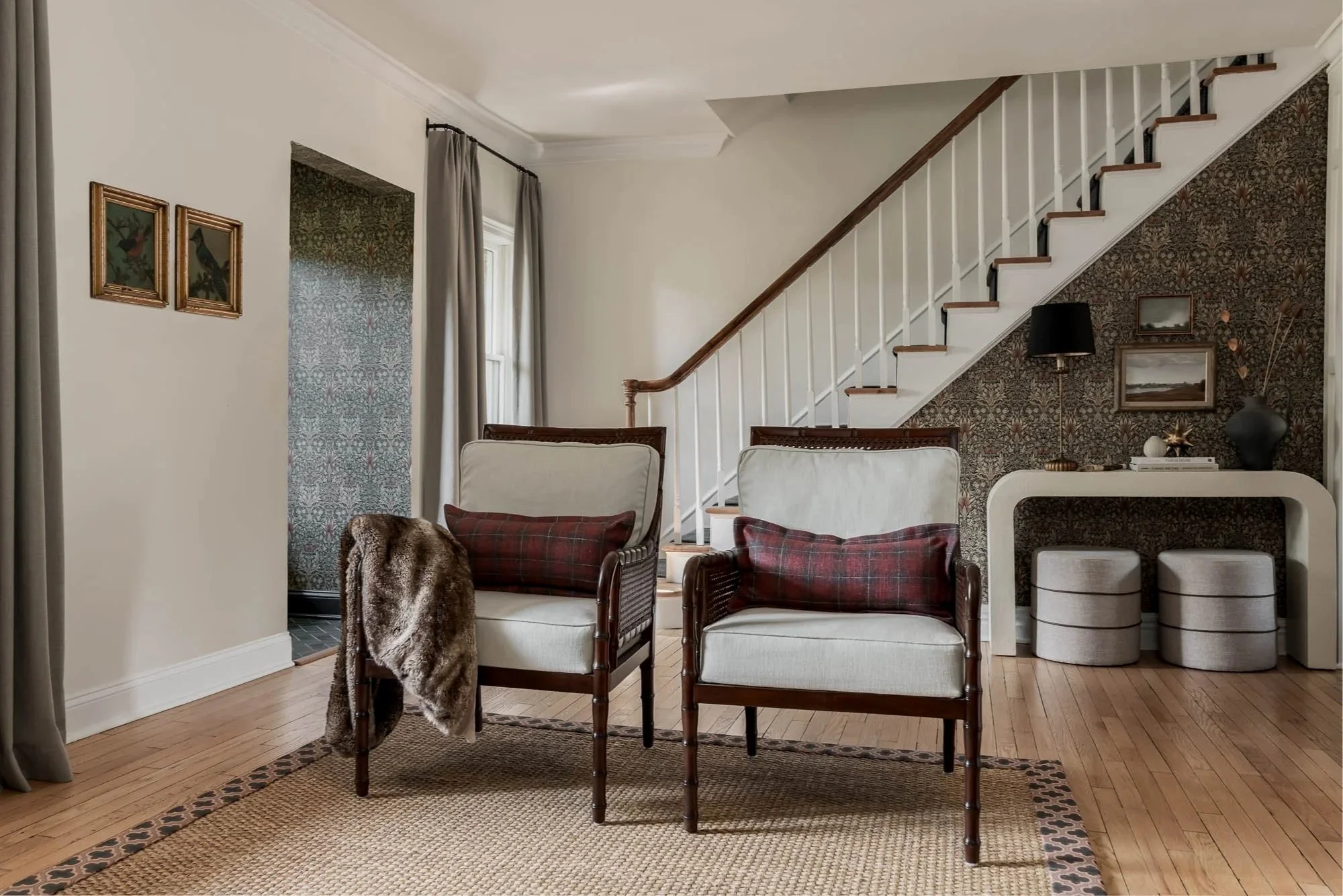Living room with three chairs, a rug, staircase, and wall decorations.