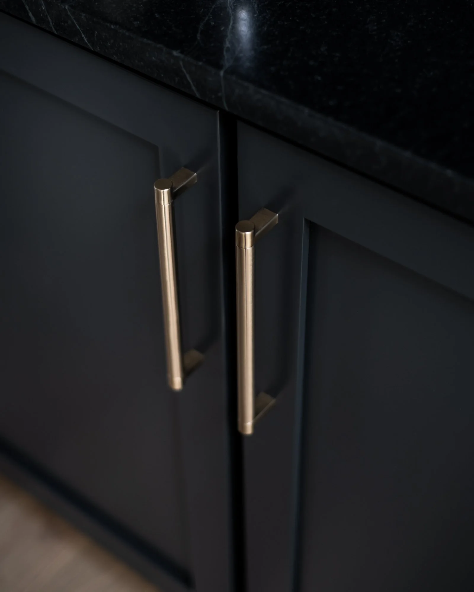 Close-up of dark kitchen cabinet doors with brushed gold handles