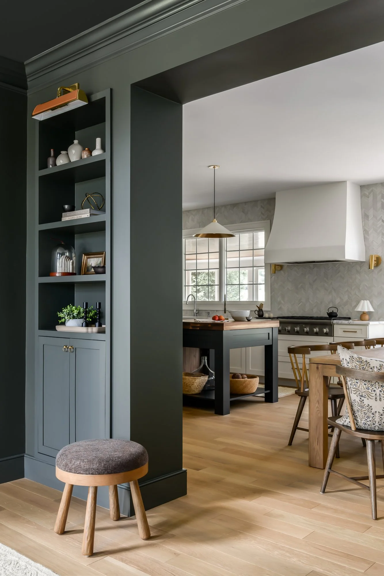 Open kitchen with dark built-in cabinetry, marble backsplash, white range hood, and layered furnishings