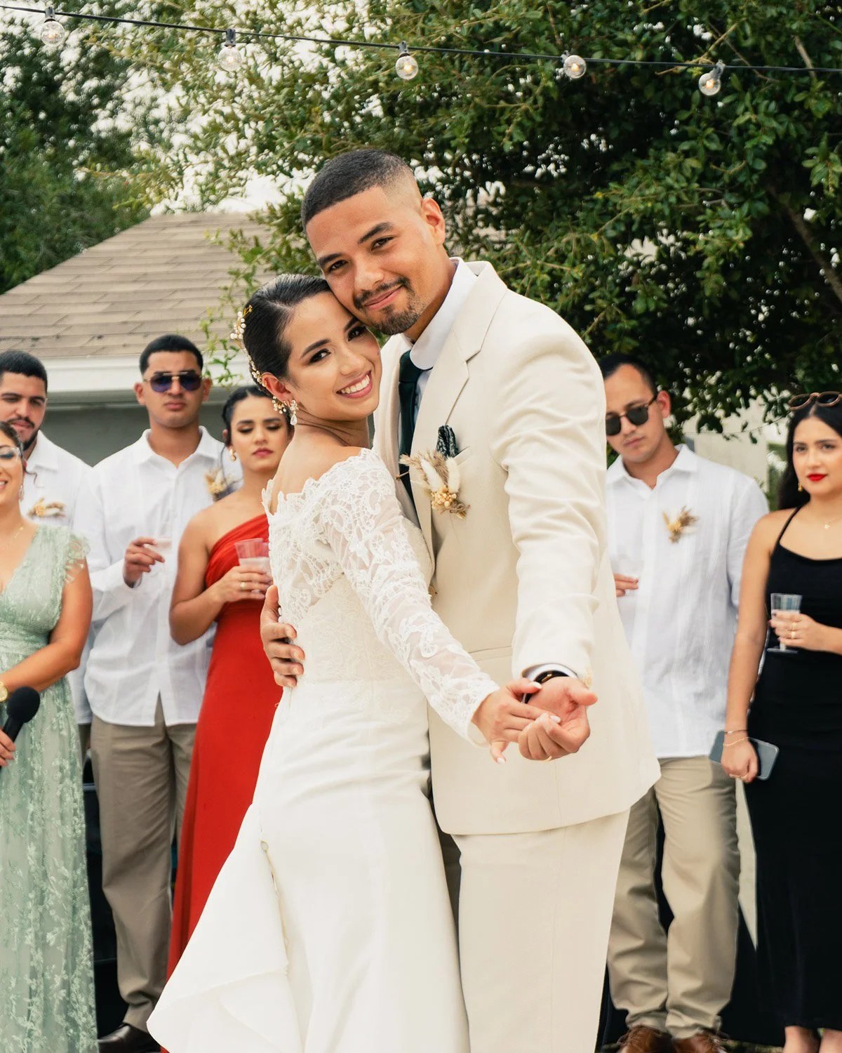 Pareja de recién casados bailando en una boda al aire libre con invitados observando.