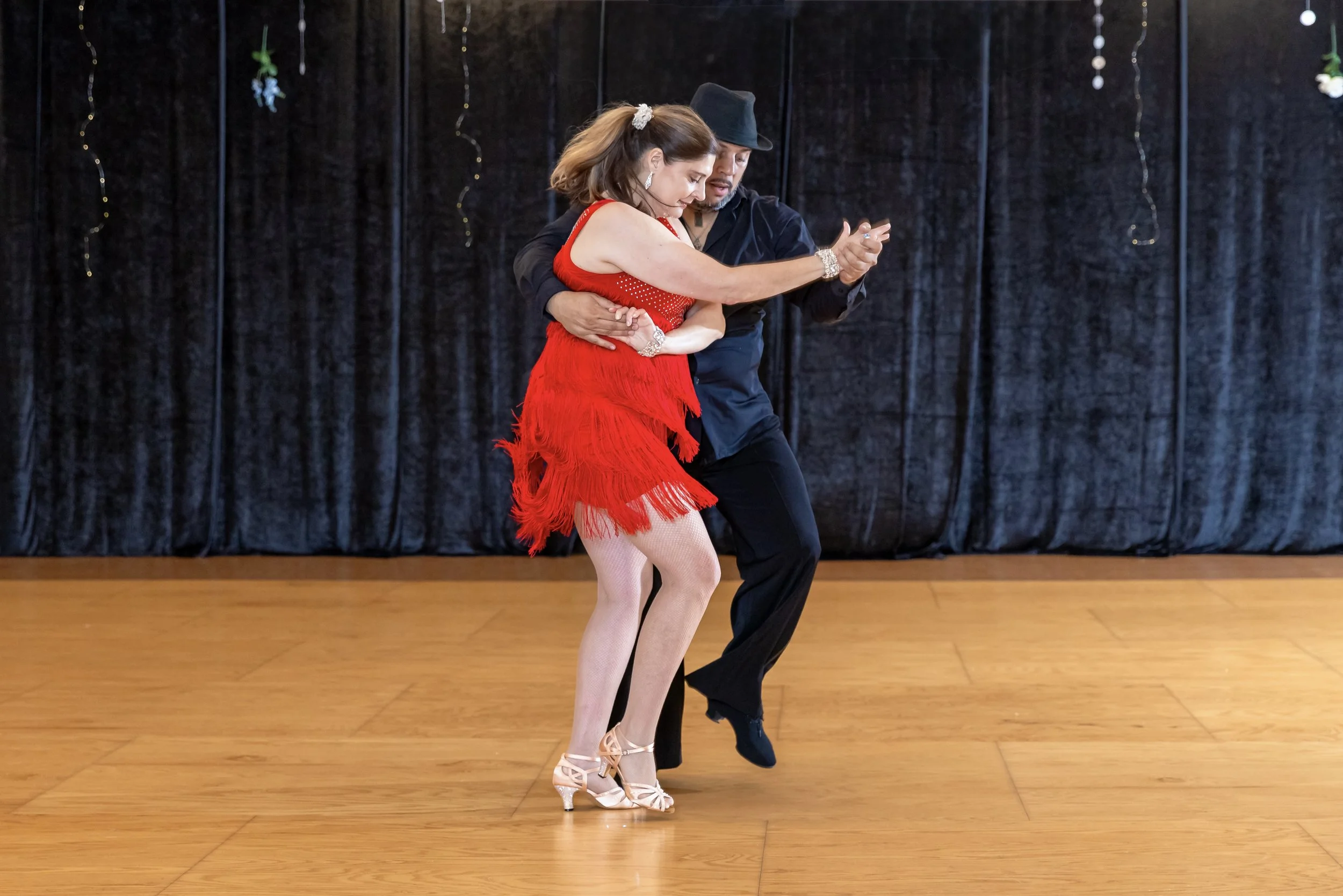 Couple performing Bachata on stage at All About Ballroom.