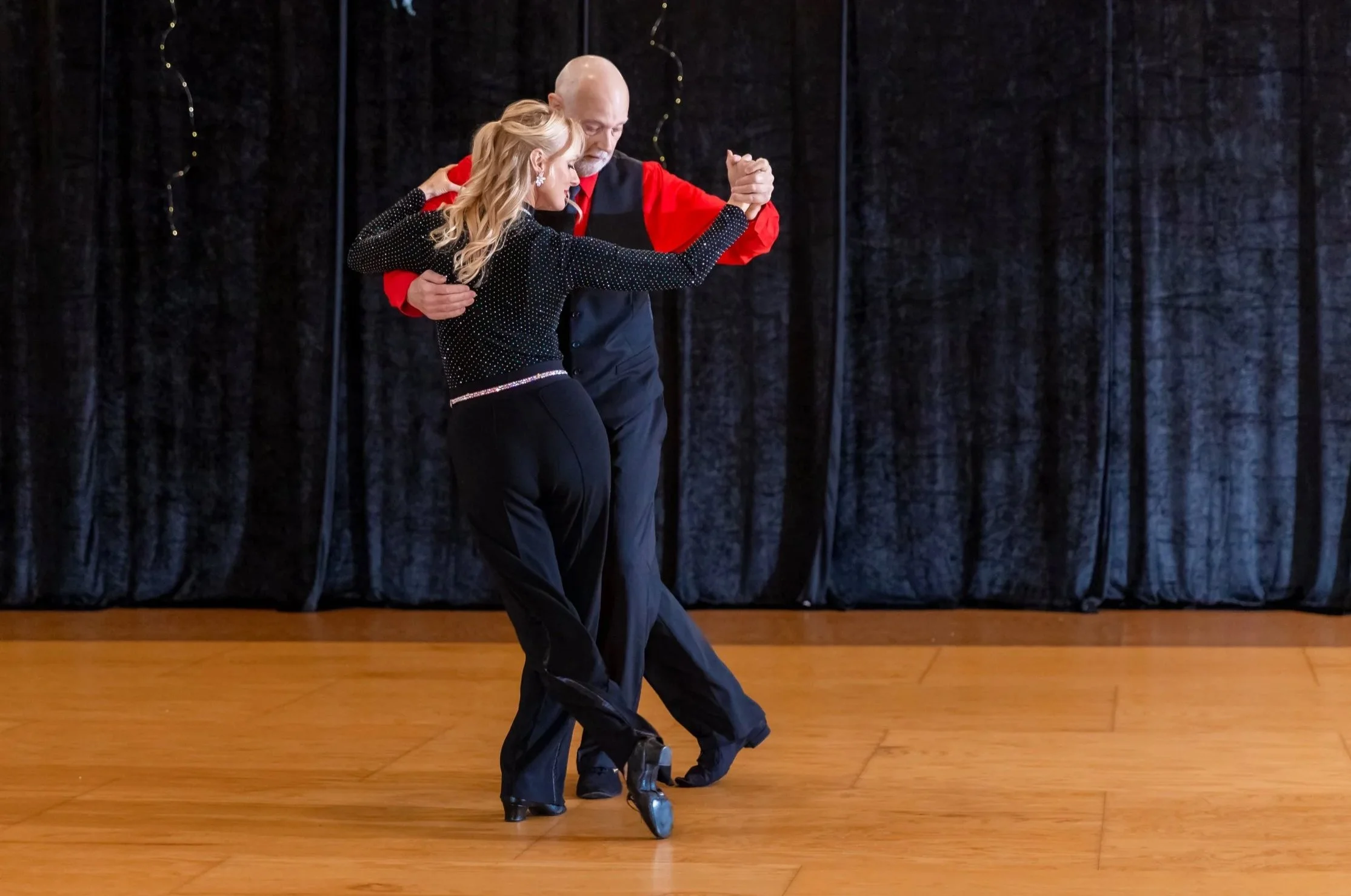 Couple performing Argentine Tango on stage at All About Ballroom.