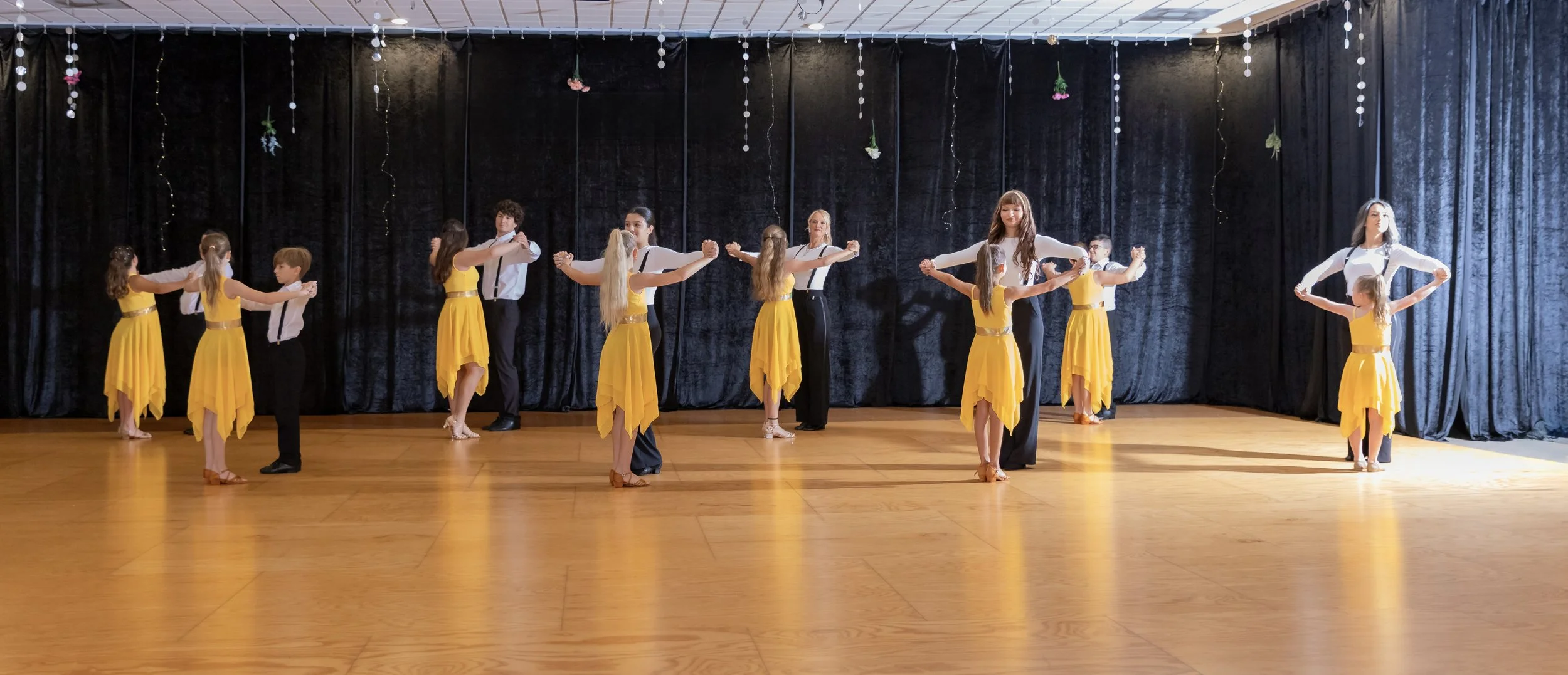 Junior Ballroom students performing a group Waltz routine at an All About Ballroom showcase.