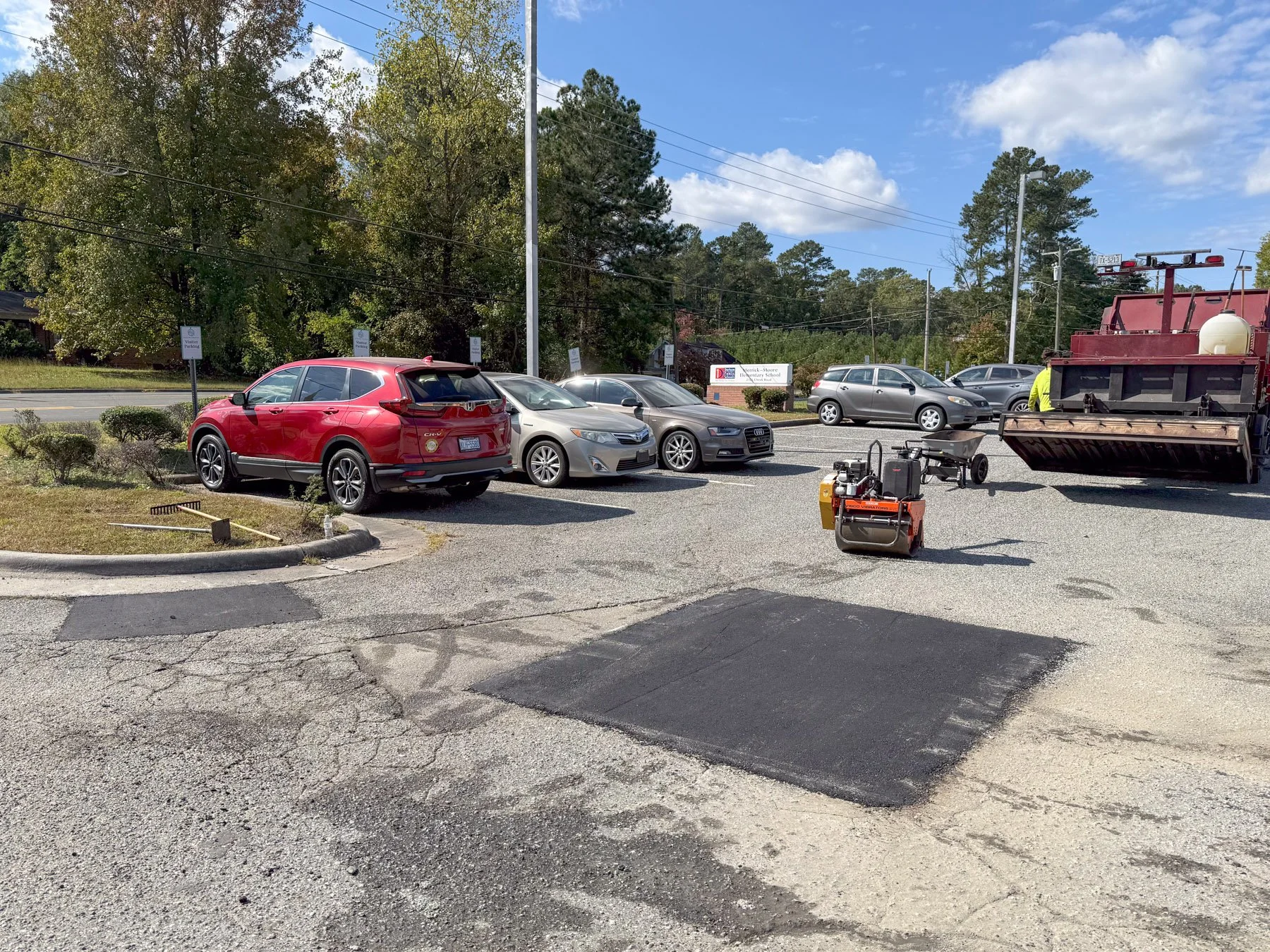 Asphalt roller and repair equipment staged in school carpool lane, Durham NC
