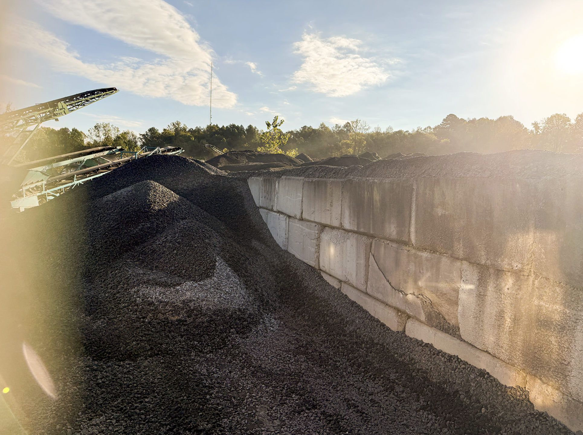 Recycled asphalt millings beside a concrete block retaining wall at a paving supply yard in Durham, NC.