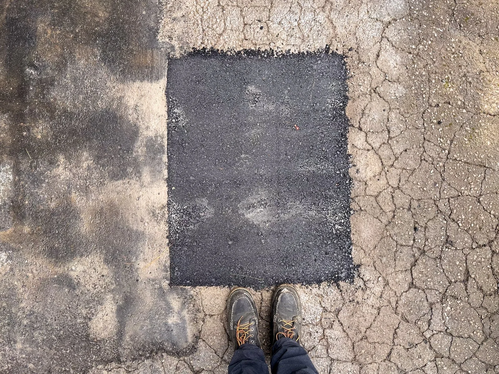 Freshly patched square of new asphalt after a cut-and-patch pothole repair in Durham, NC.