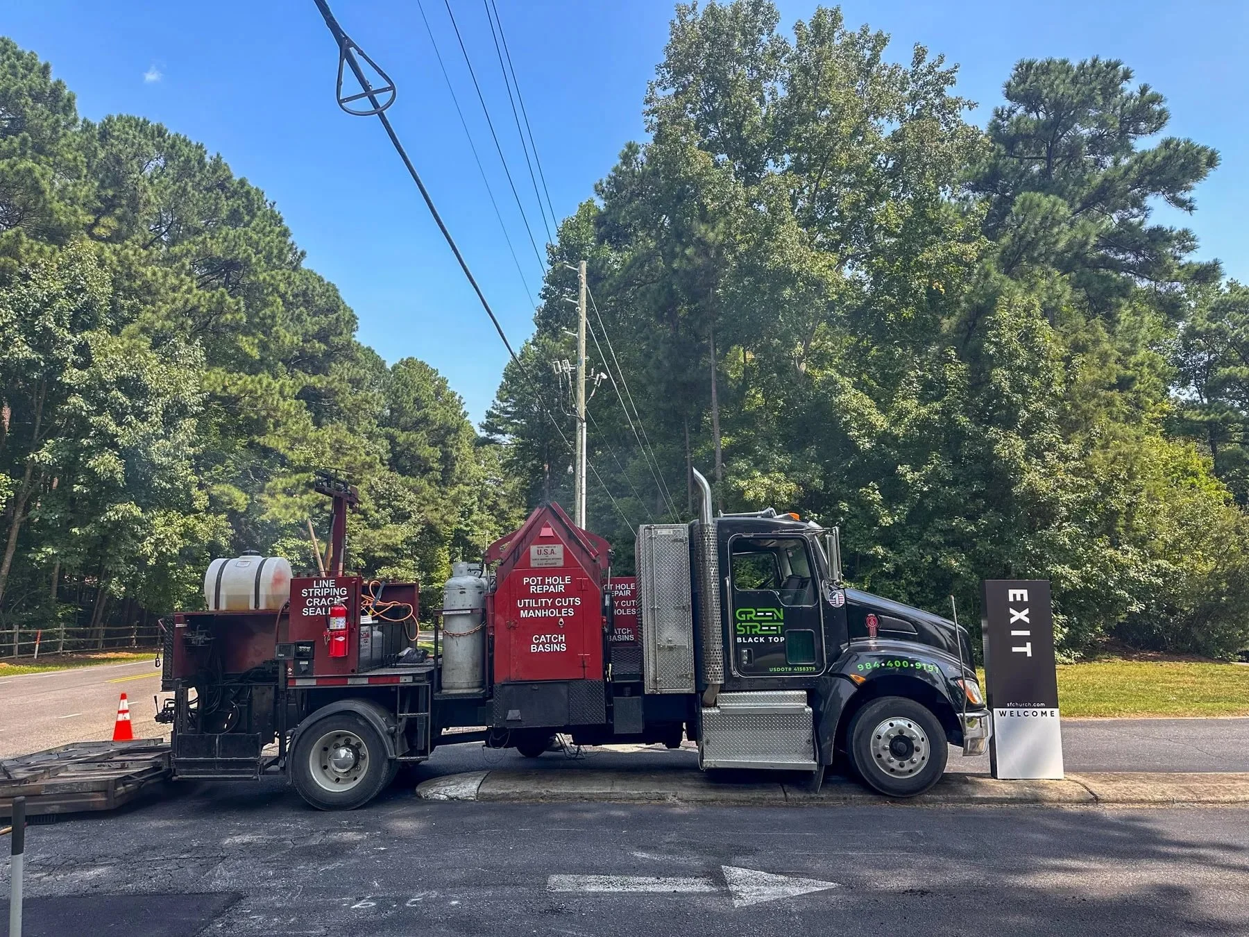 A Green Street Blacktop service truck parked outside Southbridge Fellowship in Raleigh, NC, with pothole repair, utility cut, manhole, catch basin, and line striping/crack seal service signage on the truck bed.