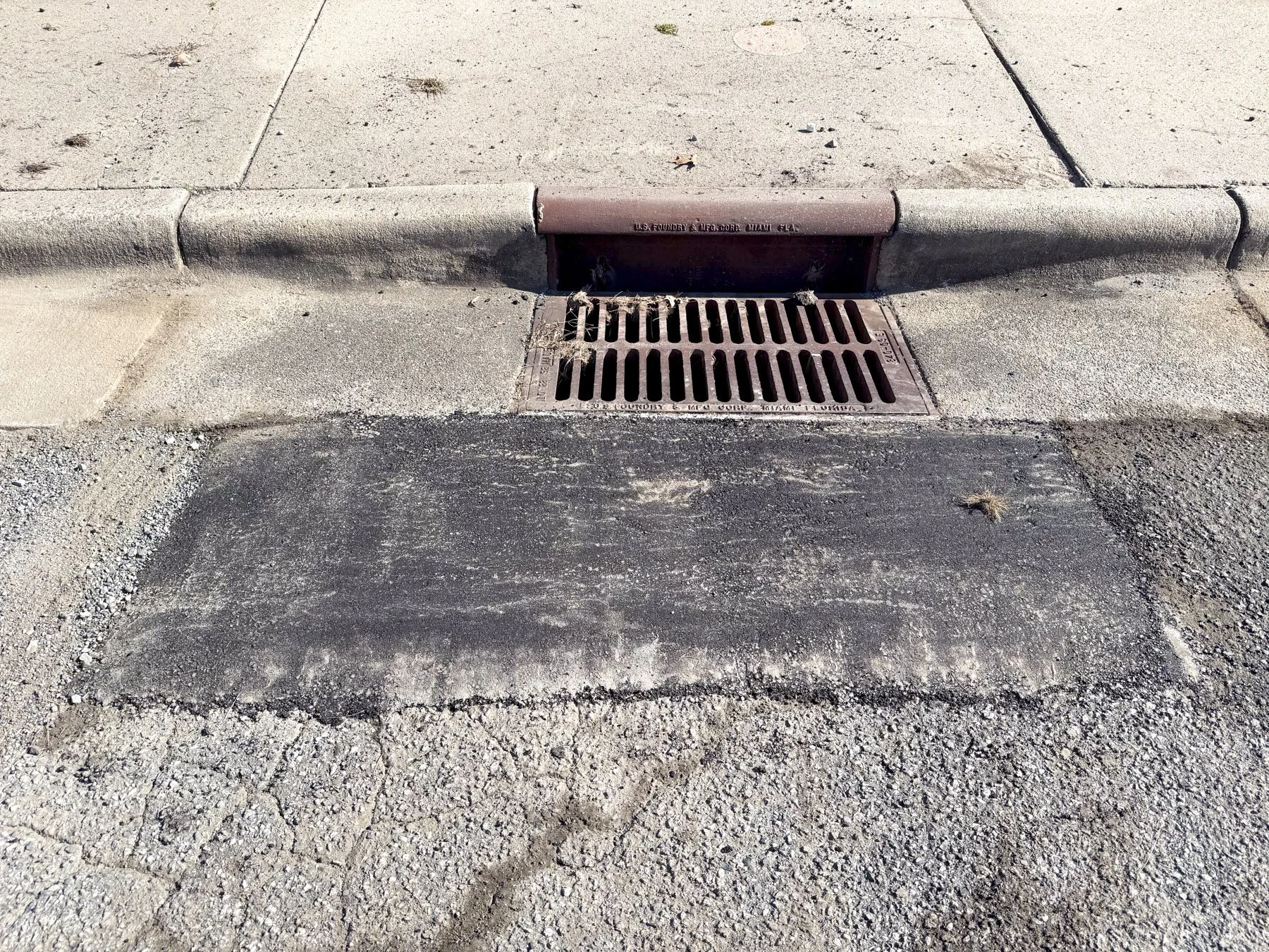 Completed asphalt patch around drain catch basin after infrared repair, Durham NC