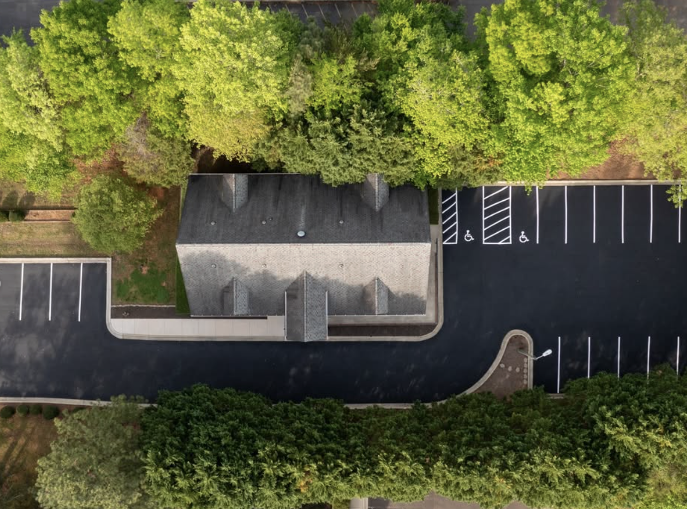 An aerial view of a freshly sealcoated and striped parking lot in Durham, NC, featuring handicap and regular parking spaces.