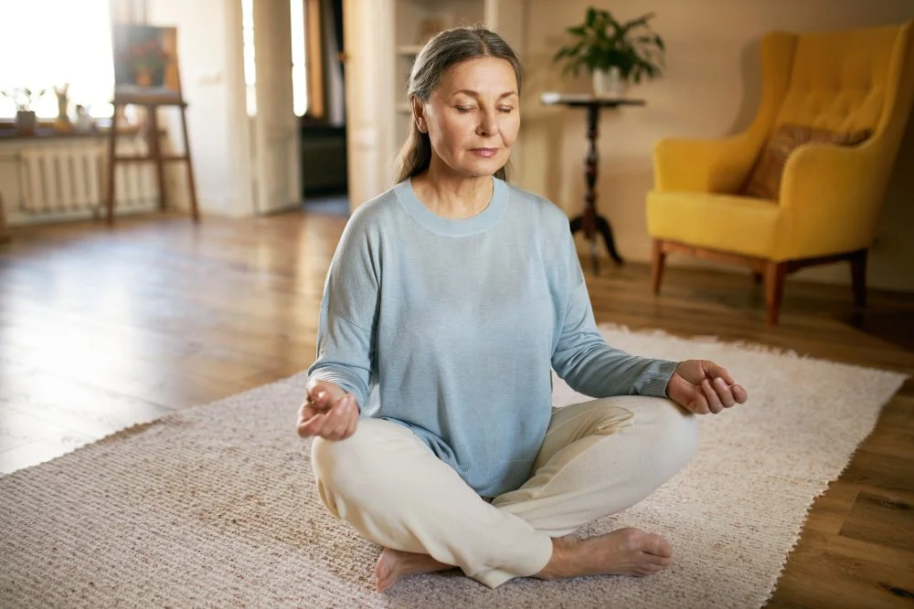A woman practicing meditation in a cozy living room.