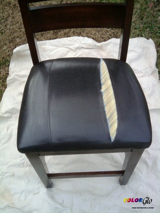 A black leather chair with an exposed foam and fabric cushion underneath, seen from above, outdoors on a white cloth.