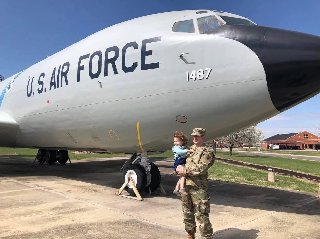U.S. Air Force airplane on display outdoors with candidate holding his daughter in front of it.