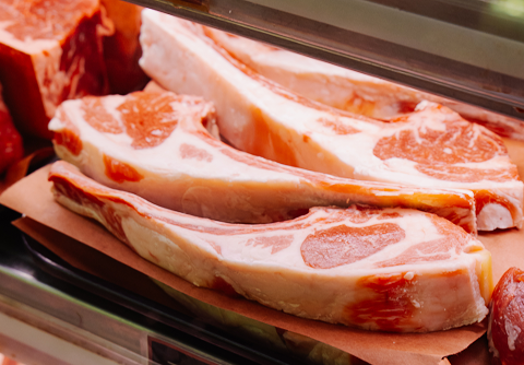 Raw pork chops in a refrigerated case.