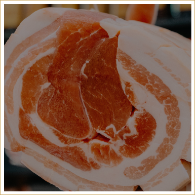 Close-up of a rolled slice of pork with layers of fat and meat.