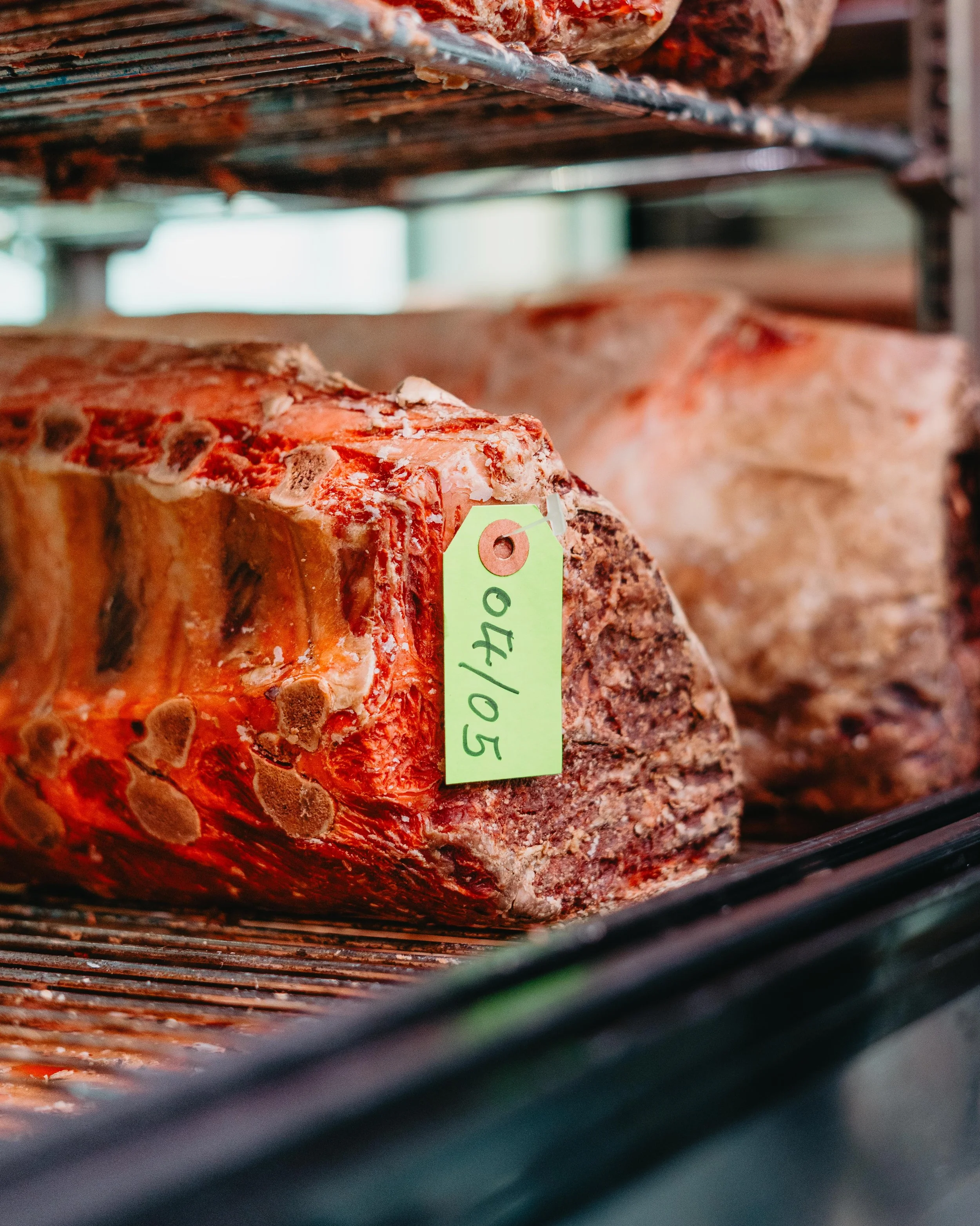 Pieces of aged meat with a green tag in a refrigerator.