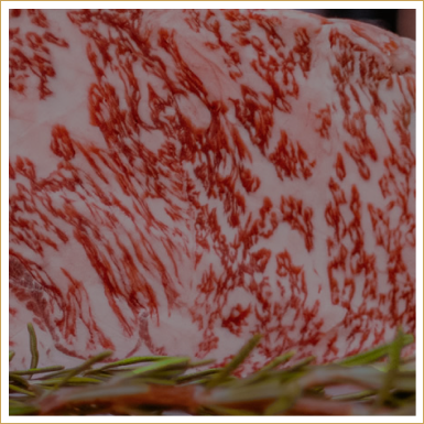 A raw, marbled piece of Japanese Wagyu beef with visible white fat streaks and a sprig of rosemary in the foreground.