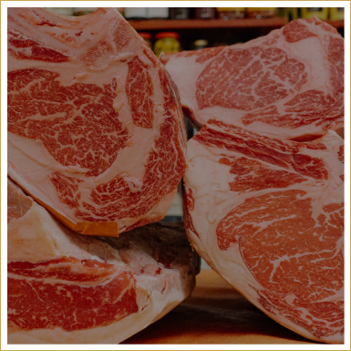 Various cuts of marbled beef on a cutting board in a butcher shop.