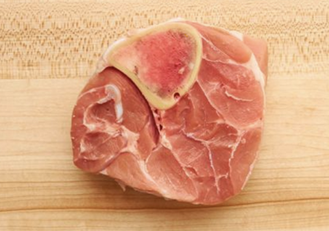 A piece of raw pork placed on a wooden cutting board.