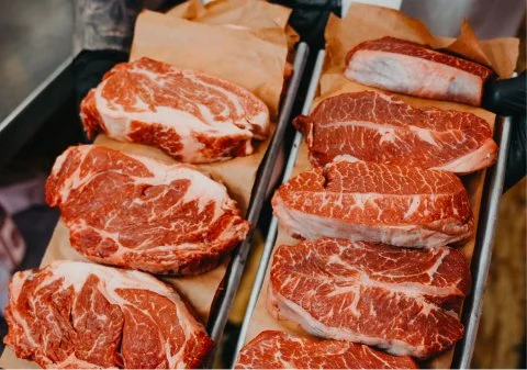 Slices of raw marbled beef on a tray, ready for grilling or cooking.