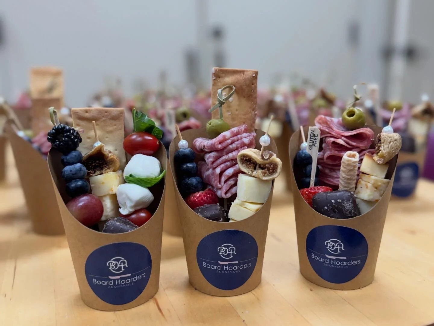 Charcuterie and fruit cones with cheese, meats, berries, olives, and grapes on a wooden table.