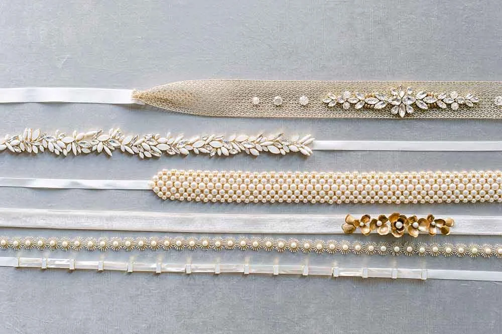 Six different pearl and bead headbands laid on a light gray surface.