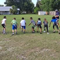 Group of children playing a game on a grassy field in a park.