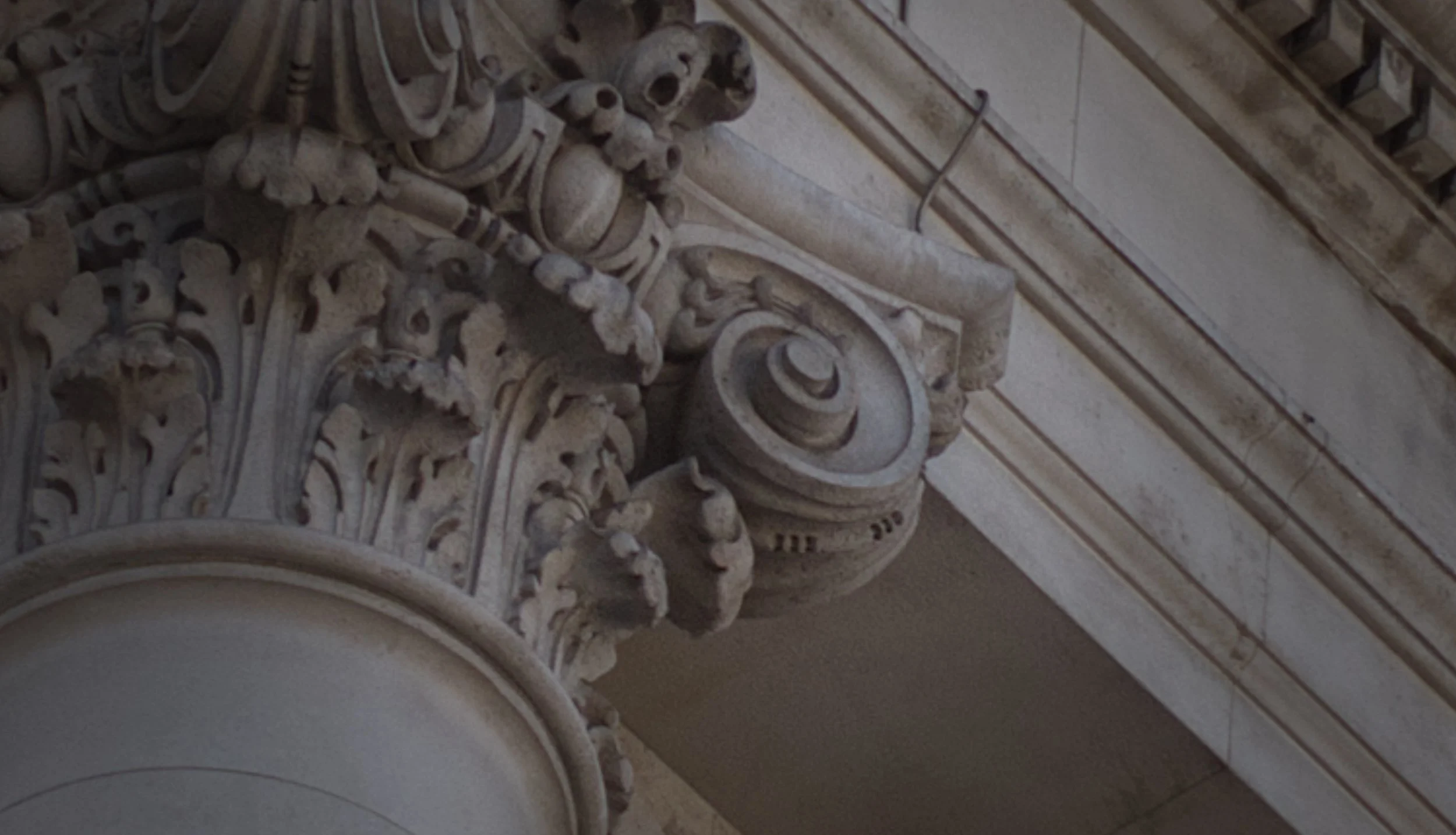 Close-up of intricate stone or wood carvings on an architectural structure, including a decorative cornice and ornamental details.