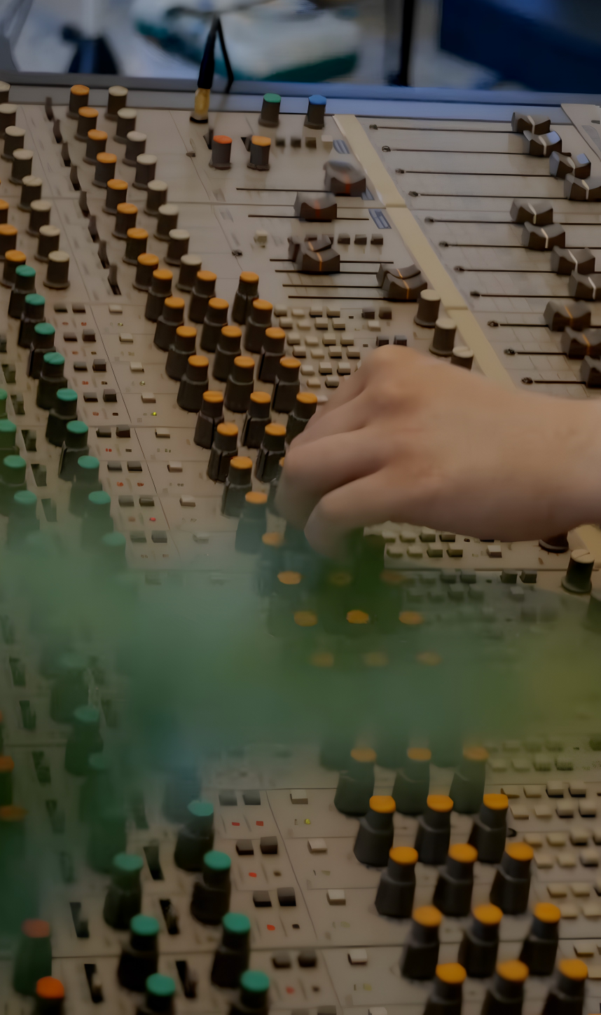 Hand justerar faders och knappar på analogt mixerbord – professionell mixning av musik i Uppsala hos Mixrummet
