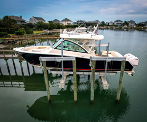 A boat docked on a calm body of water with houses and trees in the background.