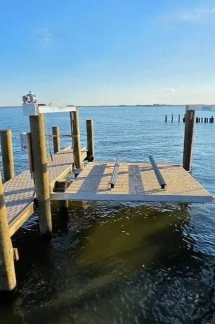 A wooden dock extending into a body of water under a clear blue sky during daytime.
