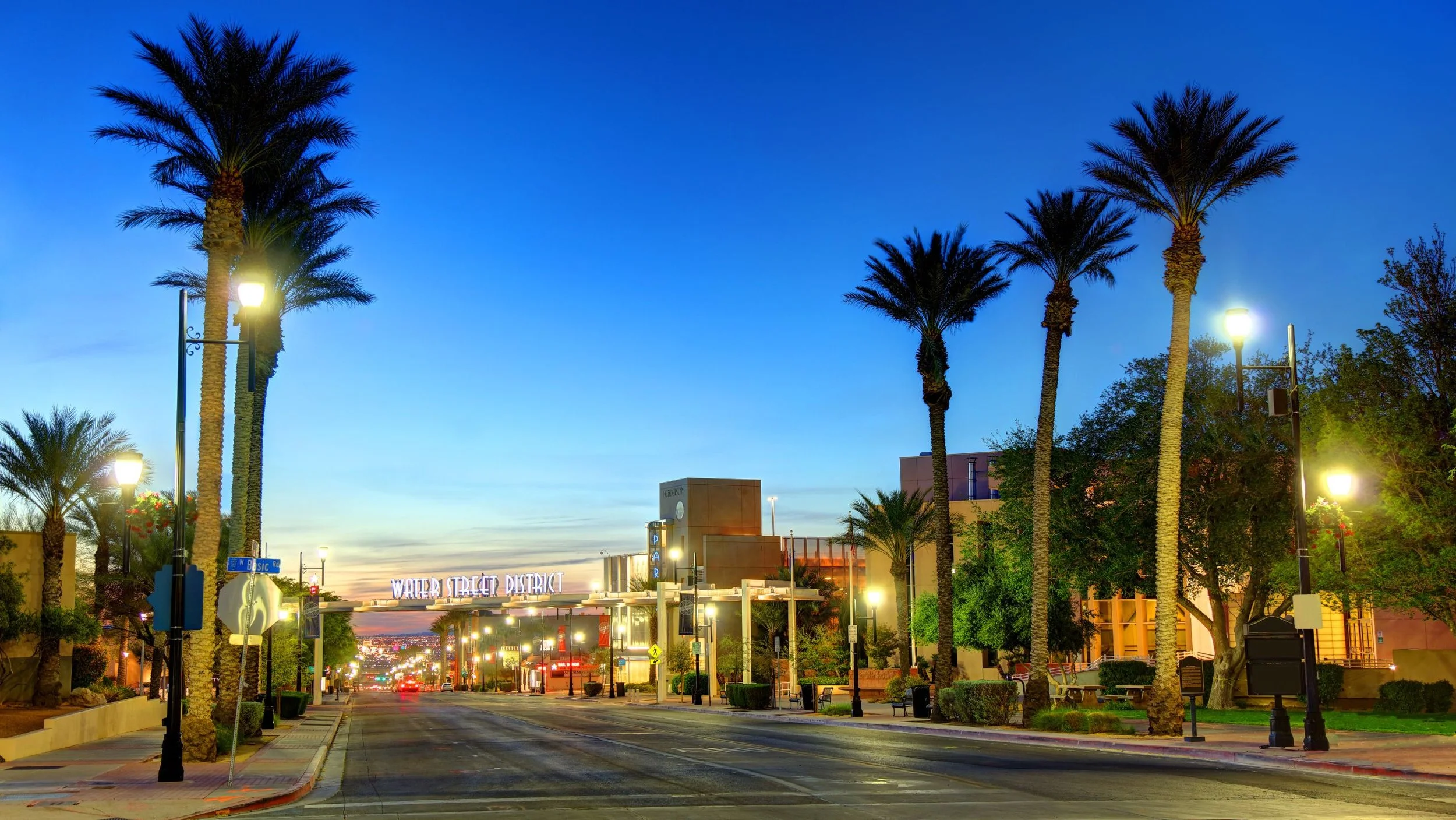 Street view of Water Street District with palm trees and street lamps during dusk.