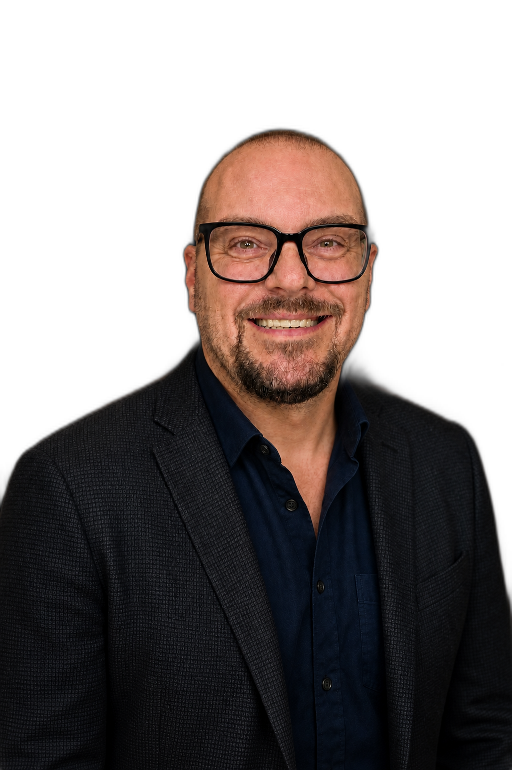 A man with glasses smiling, wearing a dark blazer and blue shirt, against a black background.