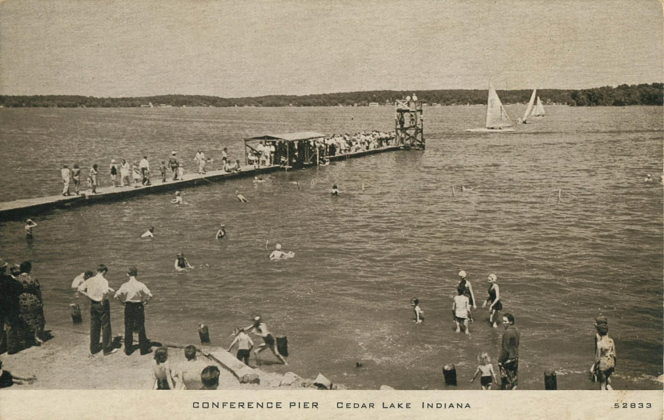 Historic black-and-white photo of people swimming and relaxing around Conference Pier at Cedar Lake, Indiana, with sailboats on the water.