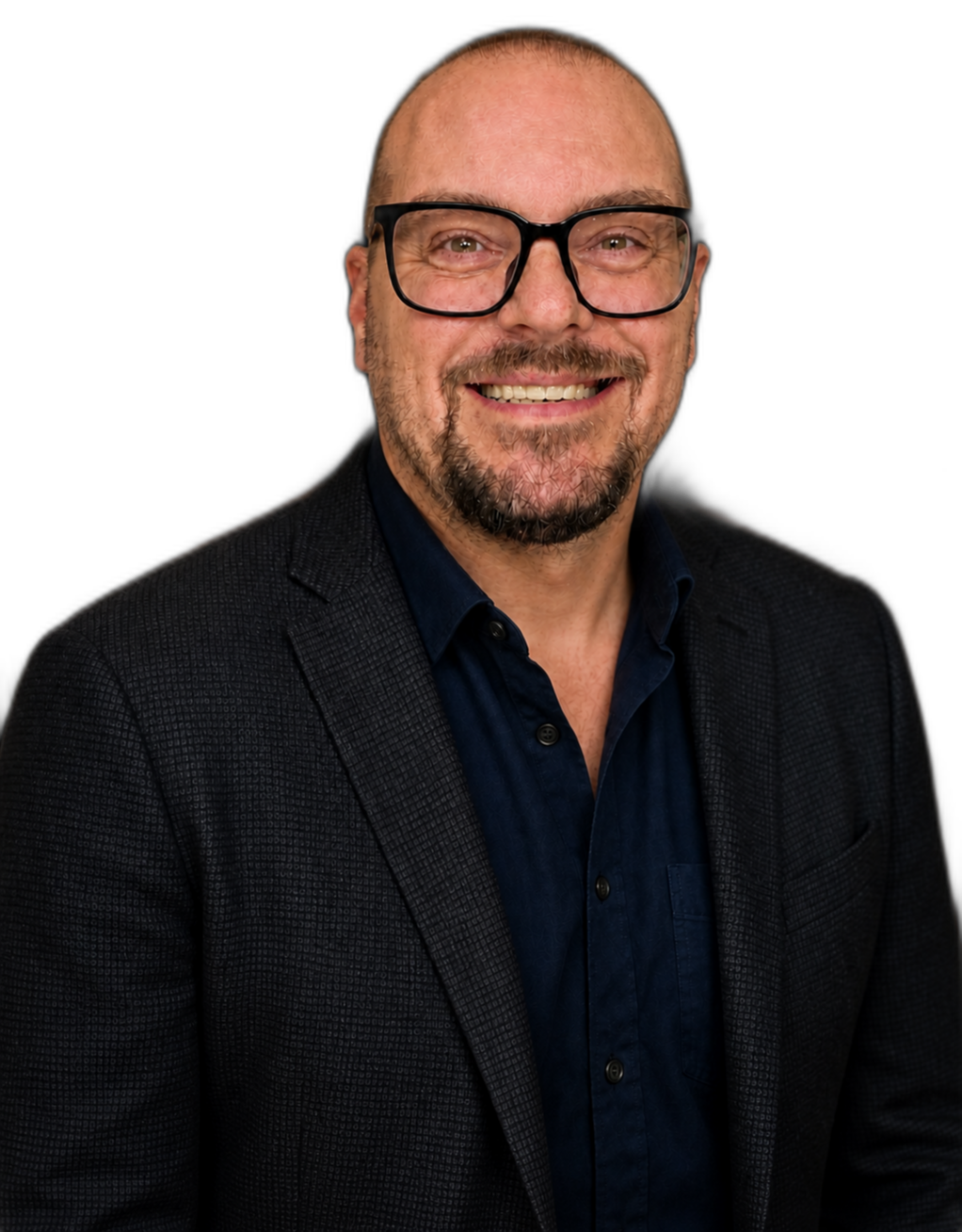 A smiling man wearing glasses, a dark blazer, and a blue shirt against a black background.