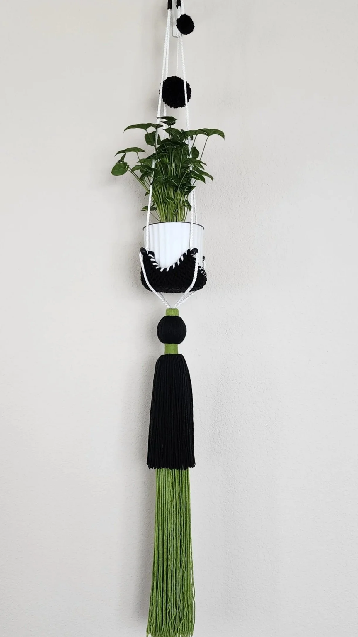 OMM Depot custom knitted plant hanger with a potted plant and decorative tassel finish