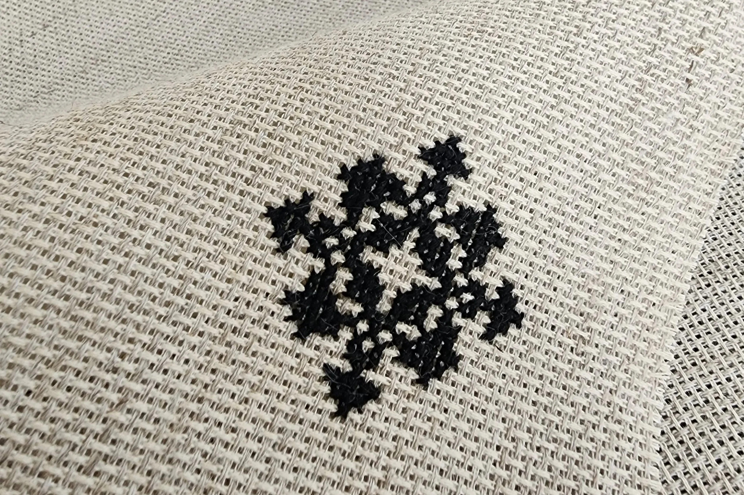 Hand embroidered Encoded Intention geometric word ornament in black cross stitch