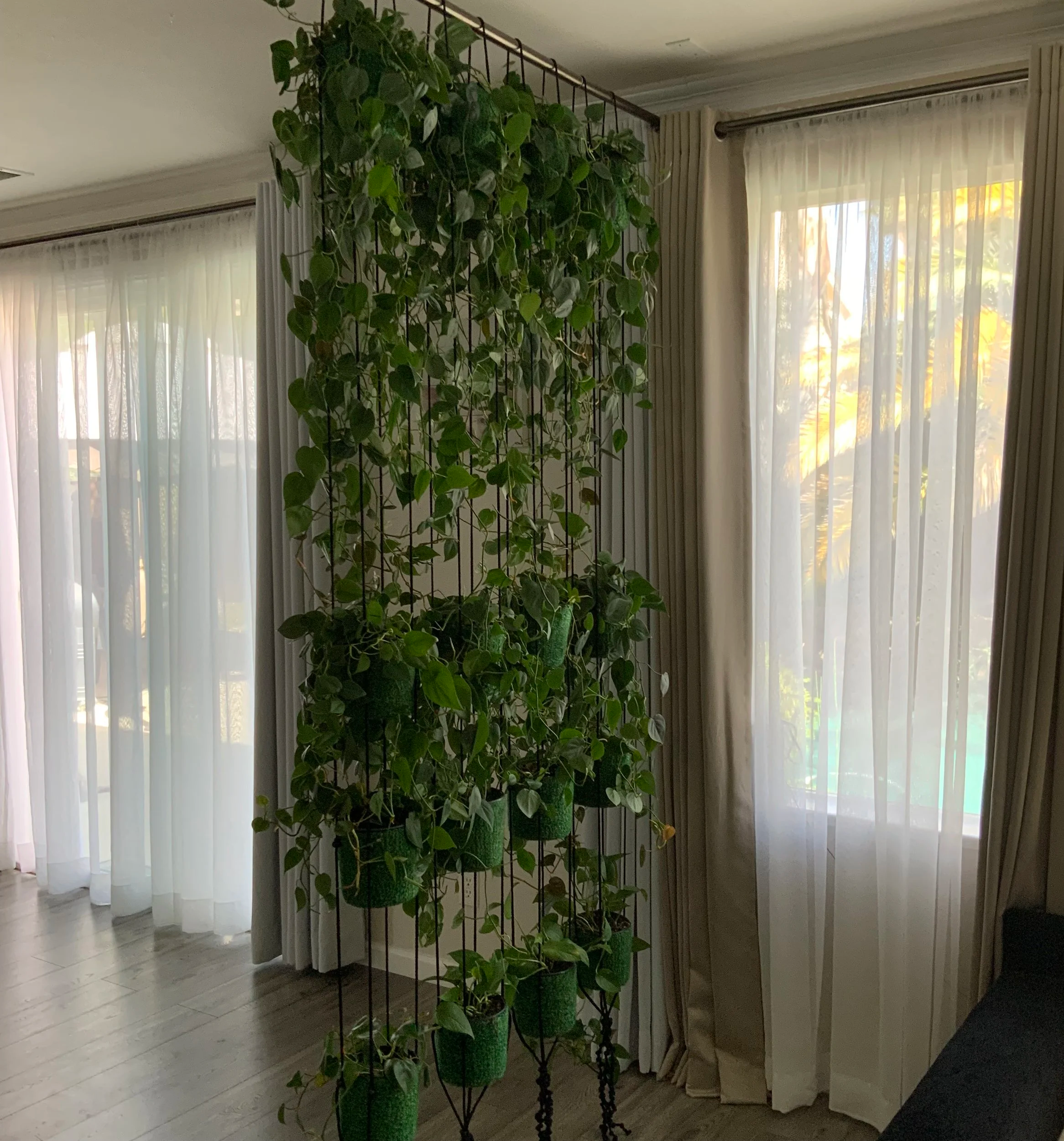 Living plant room divider made from a row of vertical hanging planters