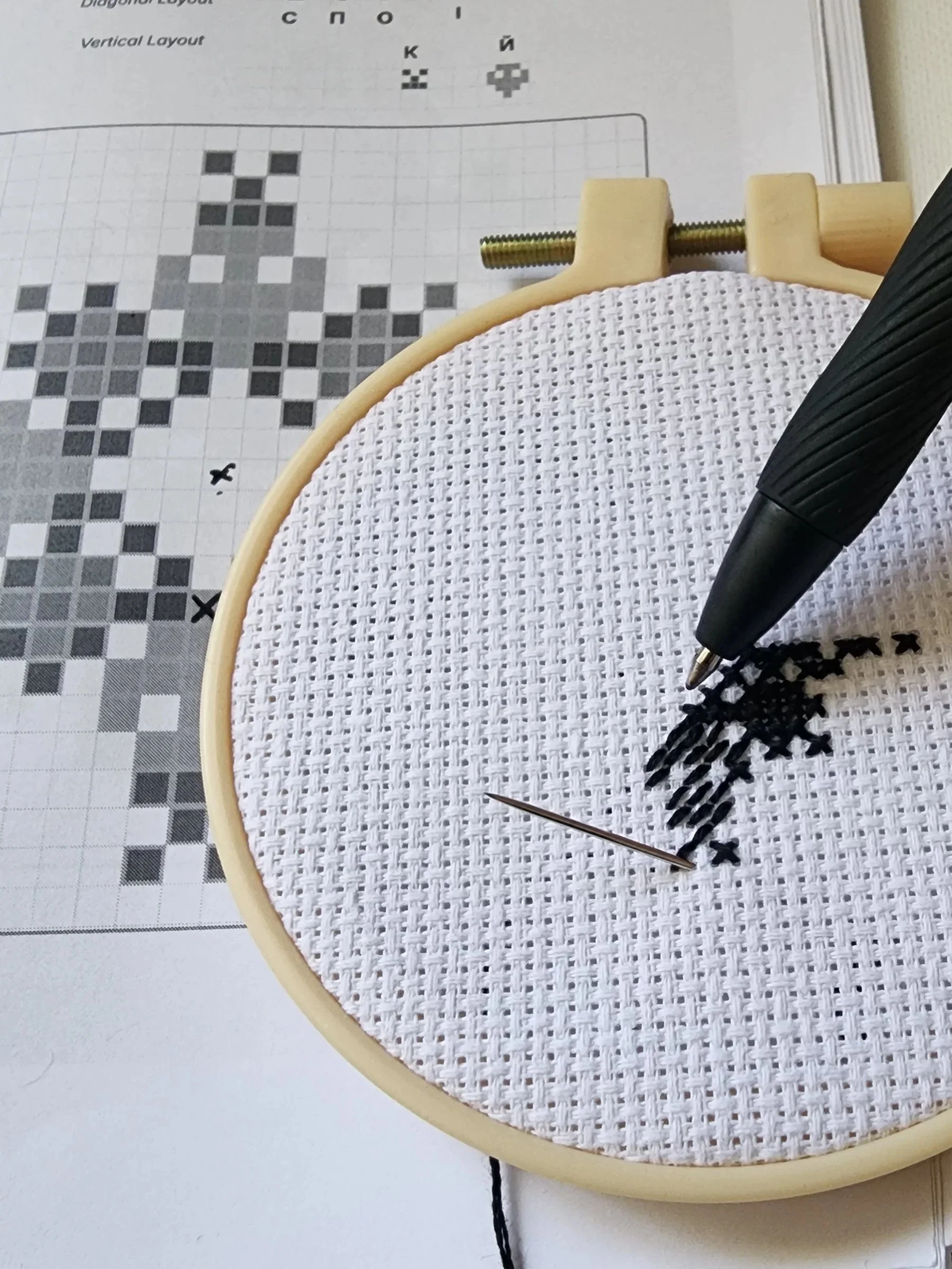 Hand embroidering an Encoded Intention geometric word ornament in cross stitch from a pattern
