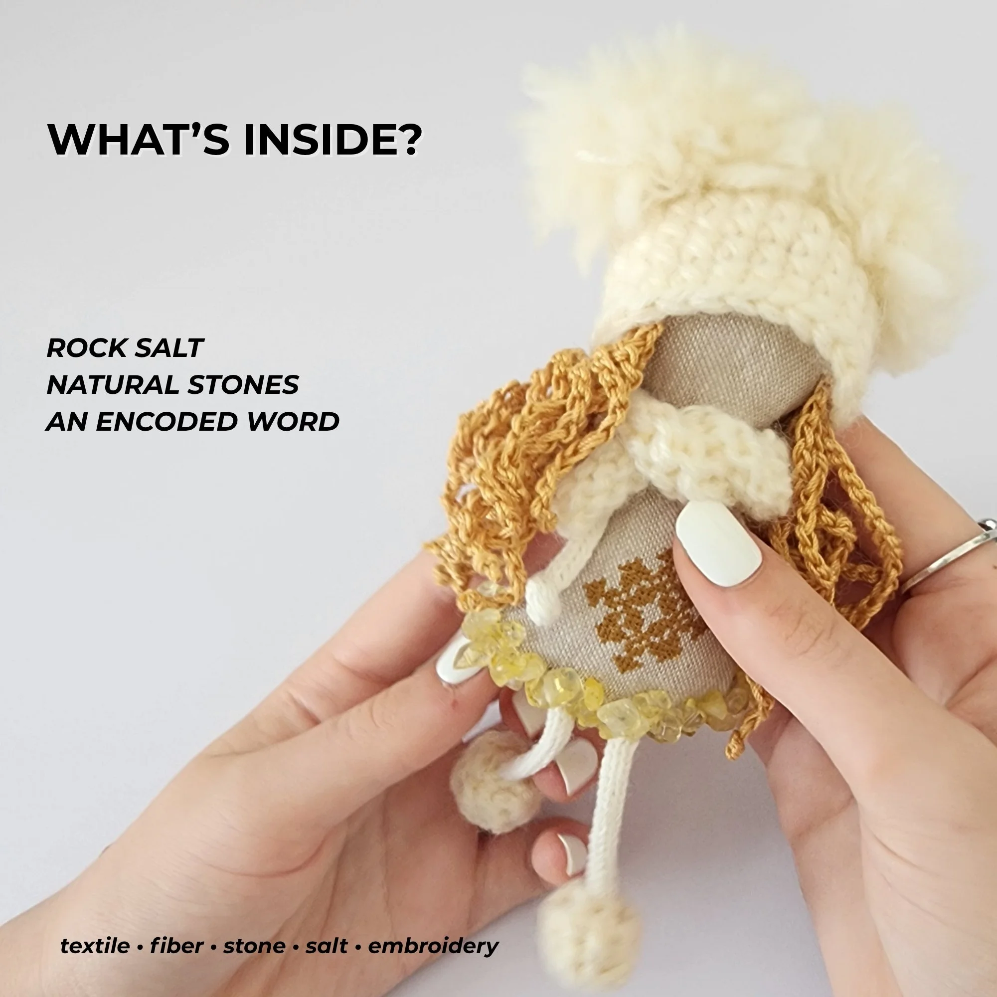 Handmade OMmi with text highlighting its materials: rock salt, natural stones, textile, fiber and an encoded embroidered word.